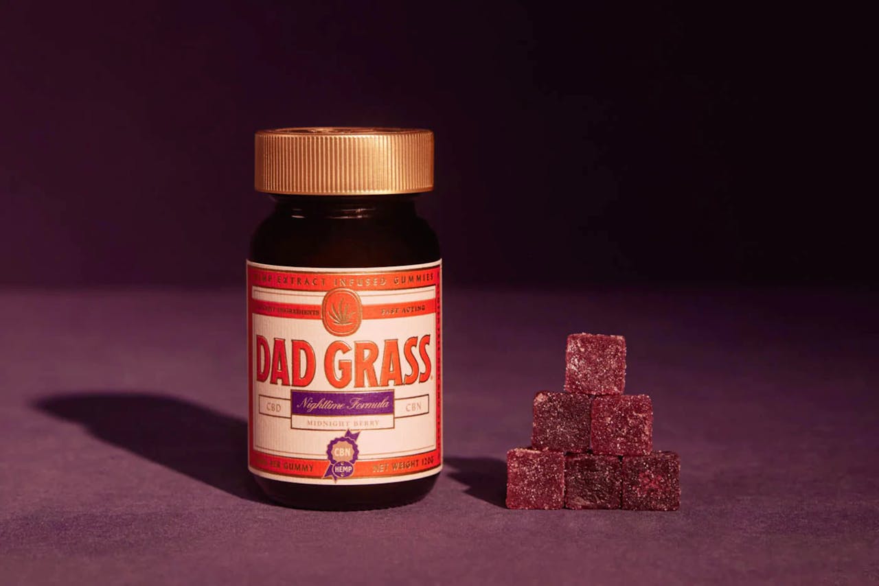 Close-up of Dad Grass nighttime CBD gummies in a jar with berry flavor.